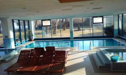 a large swimming pool with chairs in a building at Hotel Magistern Konferencia és WellnessHotel in Siófok