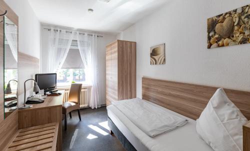 Schlafzimmer mit einem Bett und einem Schreibtisch mit einem Computer in der Unterkunft Stadt-gut-Hotel Großer Kurfürst in Emden