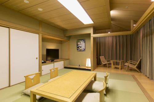 a living room with a table and a tv at Fruit Park Fujiya Hotel in Yamanashi