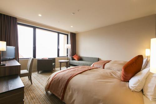 a hotel room with a large bed and a television at Fruit Park Fujiya Hotel in Yamanashi