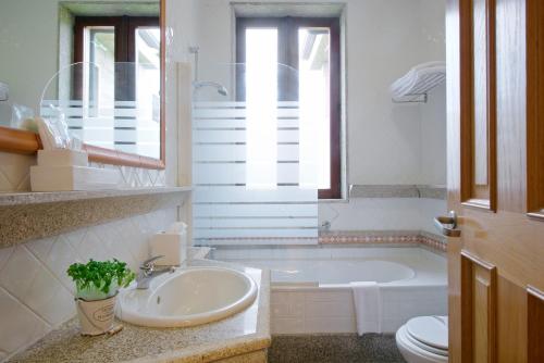 a bathroom with a sink and a tub and a toilet at Hotel de Charme Quinta do Pinheiro in Freamunde