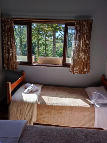 two beds in a room with a window at Pousada Vista do Lago - HOSTEL in Gramado