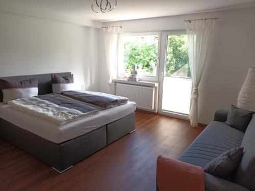 a bedroom with a bed and a couch and a window at Haus Luise Weber in Hilders