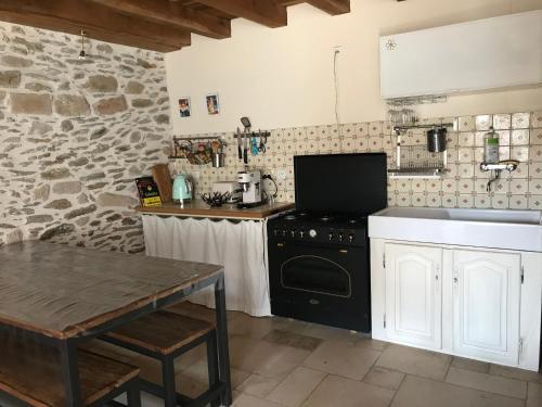 - une cuisine avec une cuisinière noire et une table dans l'établissement Maison de pêcheurs à 50 mètres de la mer, à Piriac-sur-Mer