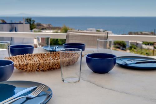 a table with plates and glasses on a table with the ocean at Captain View in Ano Syros