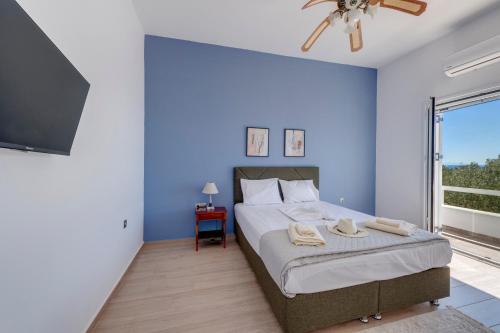 a bedroom with blue walls and a bed with a fan at Captain View in Ano Syros