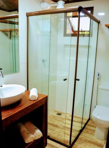 a bathroom with a glass shower and a sink at Complexo de Pousadas Caraguatá in Ilha do Mel