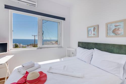 a bedroom with a large white bed with a window at Captain View in Ano Syros