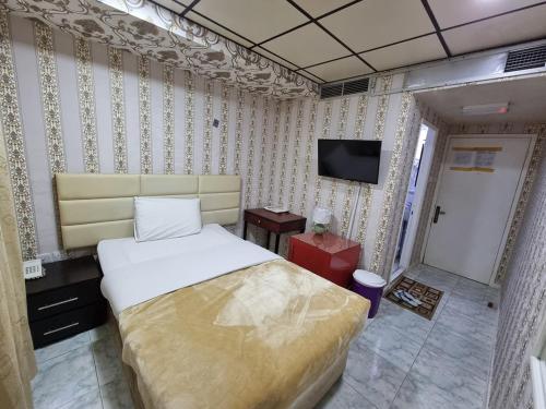 1 dormitorio con 1 cama y TV. en West Hotel, en Dubái