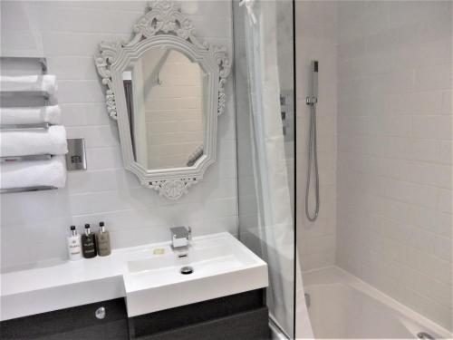 a white bathroom with a sink and a shower at THE KNIGHTWOOD OAK a Luxury King Size Bed - En-Suite Space - LYMINGTON NEW FOREST with Totally Private Entrance - Key Box entry - Free Parking & Private Outdoor Seating Area - Town ,Shops , Pubs & Solent Way Walking Distance & Complimentary Breakfast in Lymington