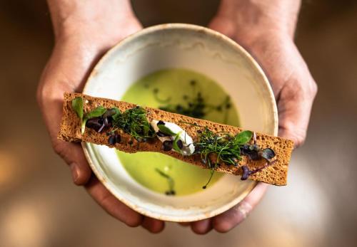 a person holding a bowl of soup and a sandwich at Hotel Kaprunerhof in Kaprun