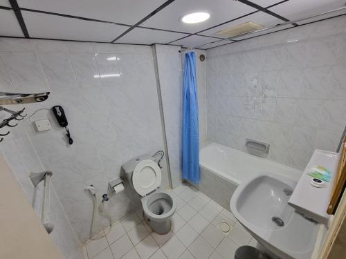 a bathroom with a toilet and a sink and a tub at West Hotel in Dubai