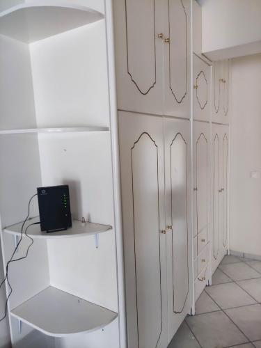 a room with white cabinets and a laptop on a shelf at GCM 1 ROOMS kentro k parking in Katerini
