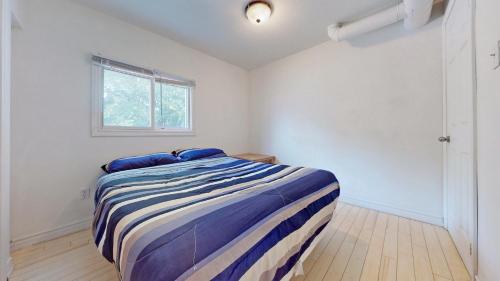 um quarto com uma cama com almofadas azuis e uma janela em Main Beach River Retreat - Wasaga Beach 1 - Main Strip - 95 Mosley St em Wasaga Beach