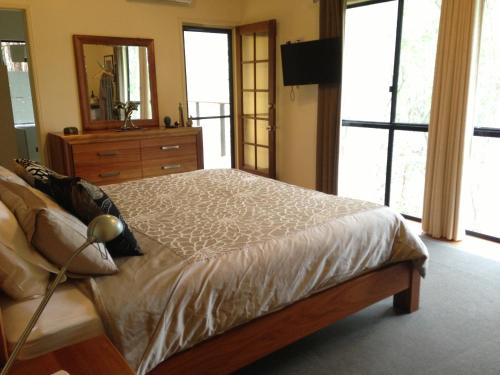 a bedroom with a bed with a dresser and a mirror at Mt Cotton Retreat in Mount Cotton