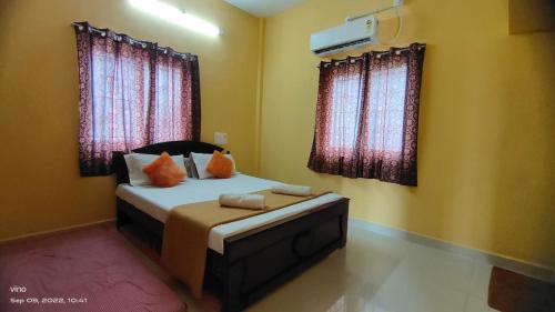 a bedroom with a bed and two windows at Aadhya guest house in Tiruvannāmalai