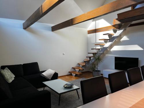 a living room with a black couch and a staircase at Villa Männituka külalistemaja in Kirikuküla