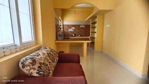 a living room with a couch and a kitchen at Aadhya guest house in Tiruvannāmalai