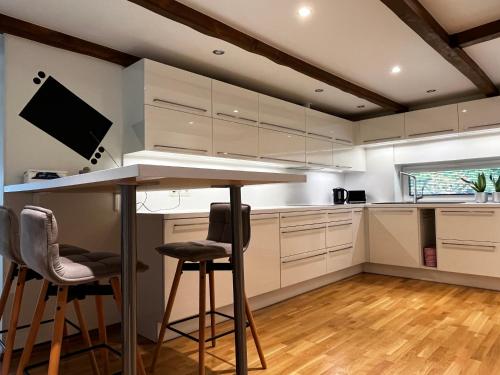 a kitchen with white cabinets and a bar with stools at Villa Männituka külalistemaja in Kirikuküla