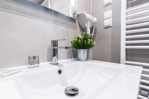 un bagno con lavandino bianco con una pianta in vaso di The Greenery Apartments a Vienna