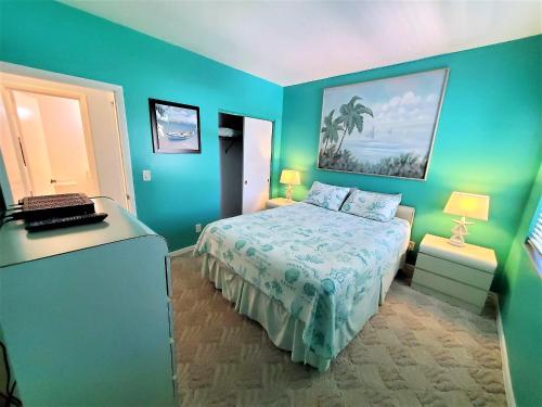 Dormitorio azul con cama y ordenador portátil en Welcome to Oasis #21 Your Coastal Retreat in Daytona Beach Shores-Walk To The Beach, en Daytona Beach Shores