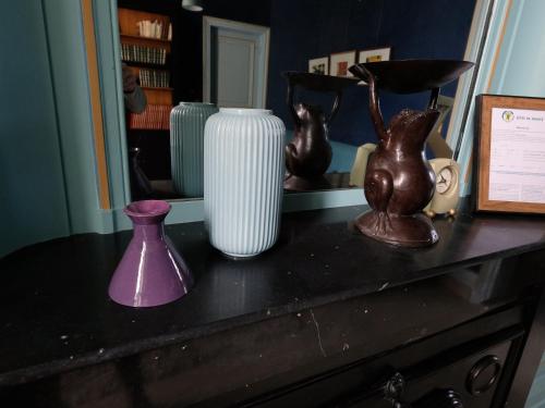 a table with vases on top of a dresser at Mille et une feuilles in Saint-Martin-lez-Tatinghem