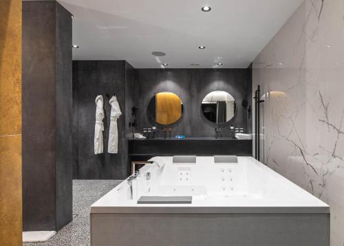 a bathroom with a white tub and two mirrors at Emily Resort in Lviv