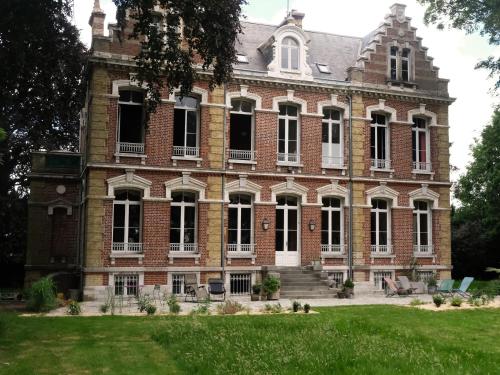 a large red brick building with a grass yard at Mille et une feuilles in Saint-Martin-lez-Tatinghem