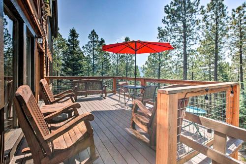 a deck with chairs and a table with an umbrella at Hot Tub, Game Room Spacious Angel Fire Retreat! in Angel Fire