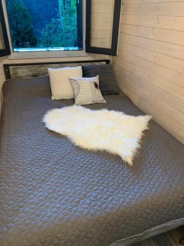 a bed with a white blanket and two pillows at Off mode - Erdei faház a tóparton in Komló