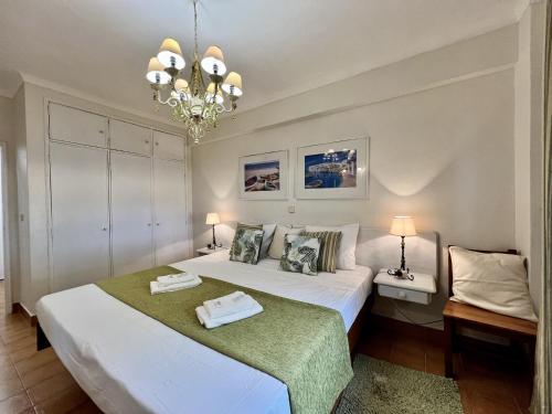 a bedroom with a large white bed and a chandelier at Albufeira Cosy by Homing in Albufeira
