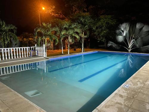 a blue swimming pool at night with palm trees at Finca Villa Sofía Campestre con piscina in Anapoima