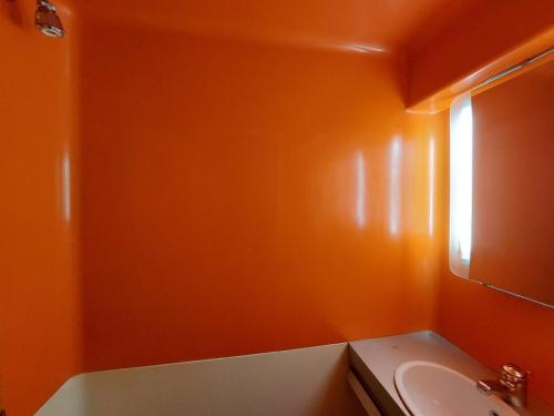 une salle de bain orange avec un lavabo et une fenêtre dans l'établissement Studio cosy pour 2, au pied des pistes et commerces, Village des Villards, Arc 1800 - FR-1-411-189, à Arc 1800