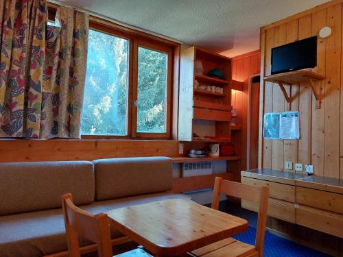 un salon avec un canapé, une table et une fenêtre dans l'établissement Studio cosy pour 2, au pied des pistes et commerces, Village des Villards, Arc 1800 - FR-1-411-189, à Arc 1800