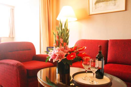 a room with a couch and a table with wine glasses and flowers at The Presidential Beijing in Beijing