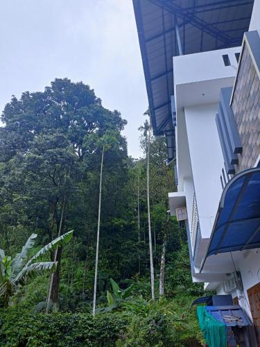 a balcony of a building with trees in the background at Nandana's Residency Munnar - A 4BHK Homestay for Indian Families in Munnar