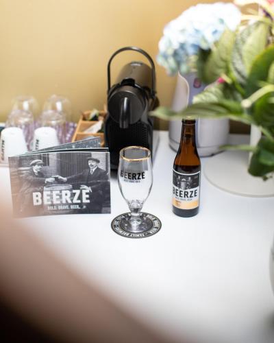 a bottle of beer and a glass on a table at Beerze Brouwerij Hotel in Vessem