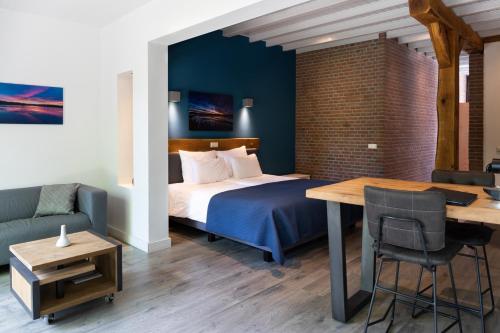 VessemにあるBeerze Brouwerij Hotelのベッド、テーブル、ソファが備わるホテルルームです。