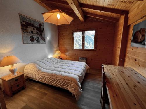 ein Schlafzimmer mit einem Bett in einer Holzhütte in der Unterkunft Murgiers B1 - Chalet mitoyen in La Clusaz