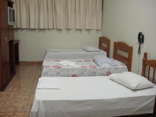 two beds sitting in a room with a television at Ouro Hotel in Ourinhos