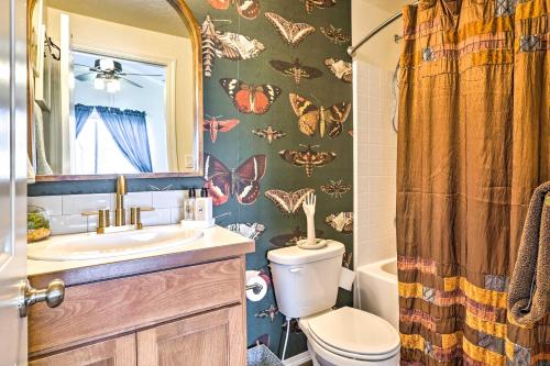 a bathroom with a toilet and a sink with butterflies on the wall at Prismatic Boise Retreat with Fenced Backyard! in Boise