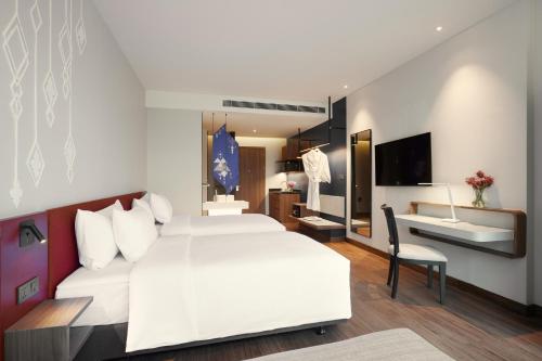 a hotel room with a white bed and a desk at Centara Life Hotel Bangkok Phra Nakhon in Bangkok