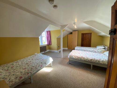 two beds in a room with yellow walls at Newport Kenvor Dinas Cross Easy access bungalow near beaches in Dinas