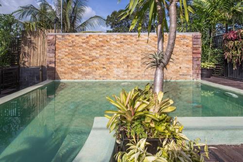 a swimming pool with a brick wall and palm trees at De Sarann Villa in Siem Reap