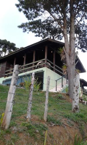 a house with a fence in front of it at Casa de campo em Monte Verde , linda vista para montanhas in Monte Verde