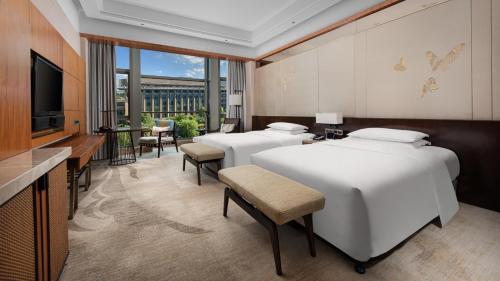 a hotel room with three beds and a television at InterContinental Kunming by IHG in Kunming
