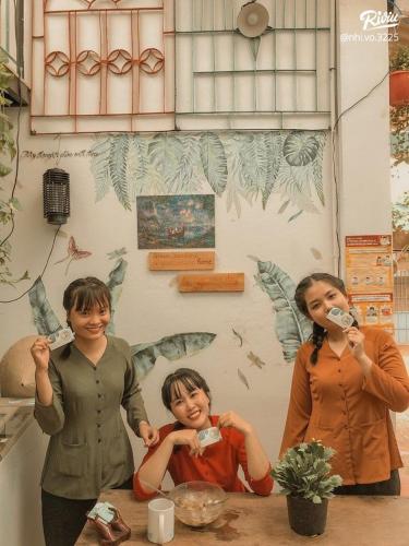 three children brushing their teeth in front of a wall at Green Sunshine Homestay in Can Tho