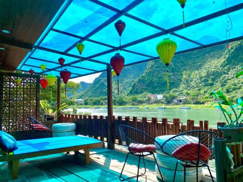 a patio with a table and chairs and a view of a river at Phong Nha Coco House in Phong Nha
