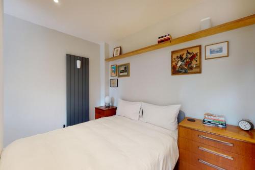 a bedroom with a white bed and a wooden dresser at Spacious 1 bedroom apartment in Kennington in London