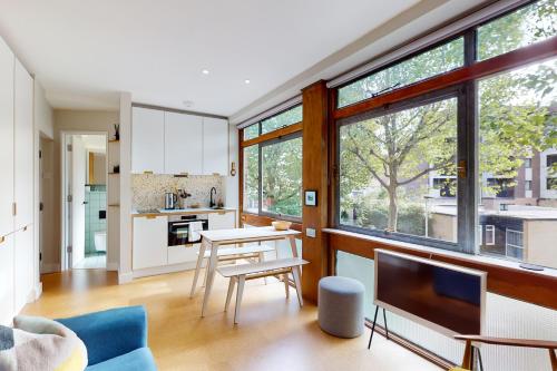 a kitchen and living room with a table and a tv at Spacious 1 bedroom apartment in Kennington in London